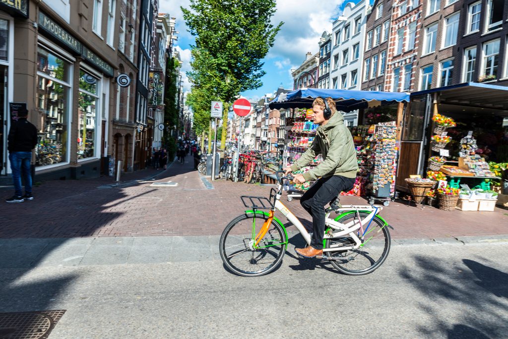 Beeld: een fietser in Amsterdam met koptelefoon